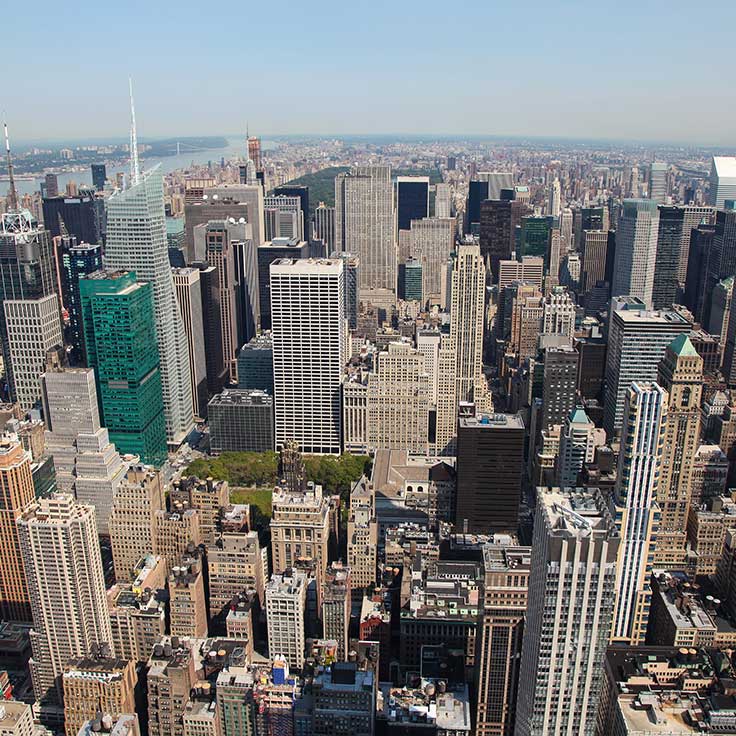 Aerial view of a dense city skyline featuring various skyscrapers and a green park amidst the buildings in New York.