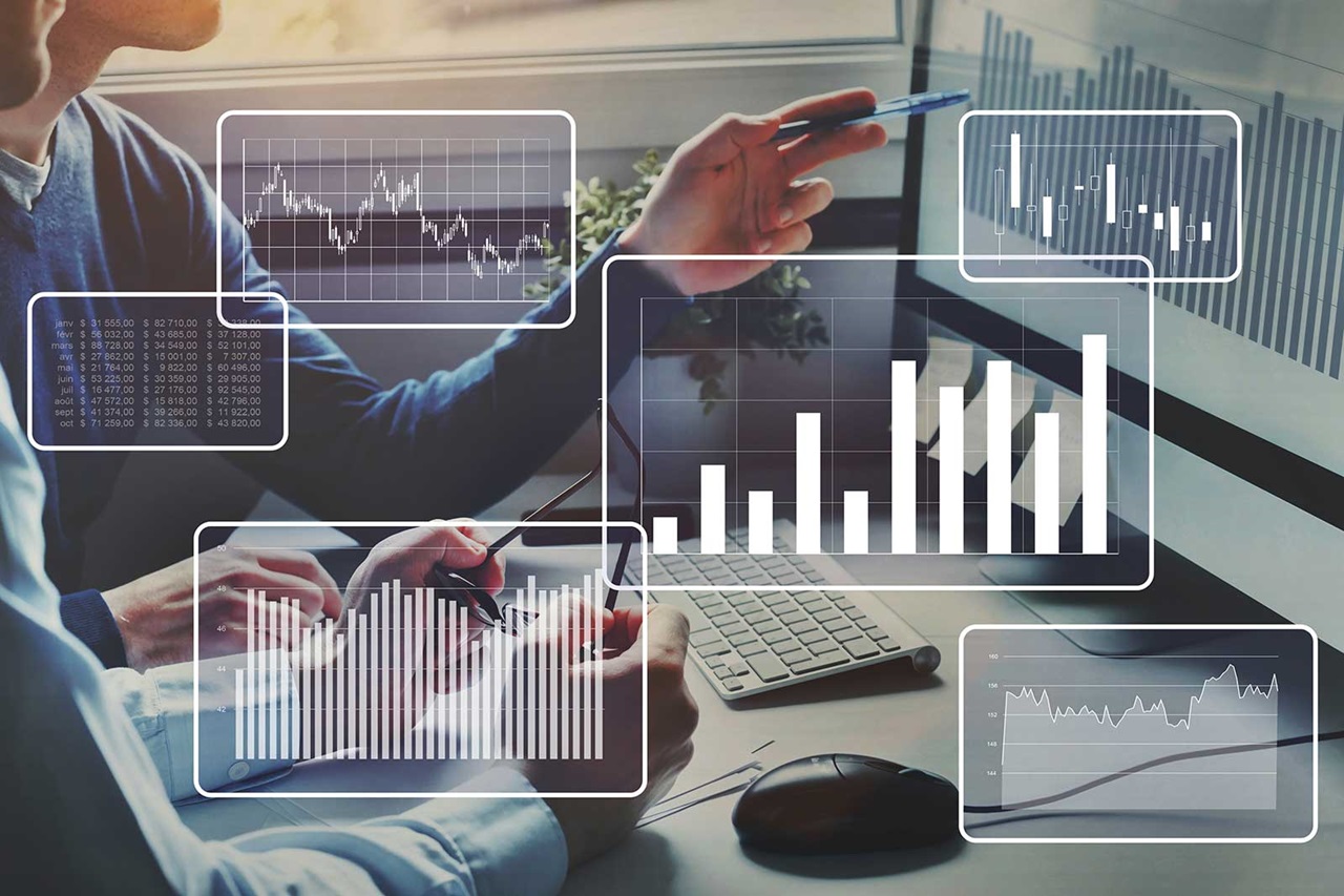 Two individuals analyse data on a computer, featuring various graphical charts and statistics related to finance.