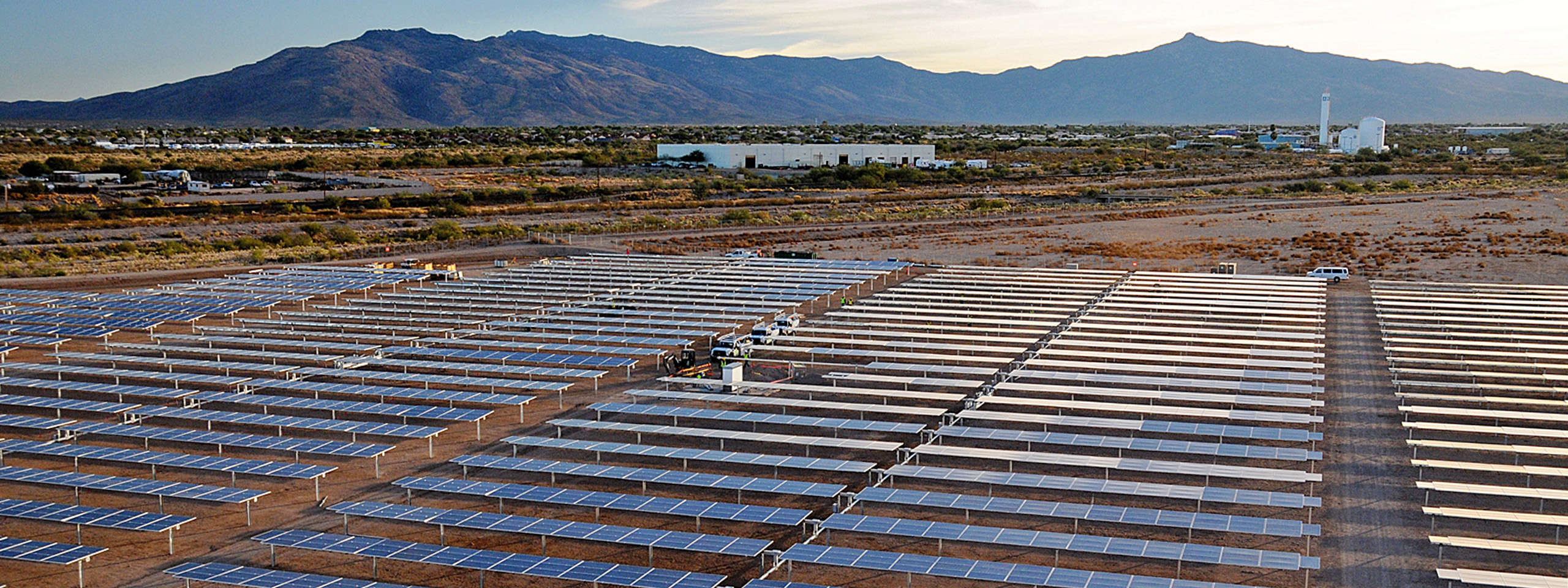 A vast solar farm featuring numerous solar panels set against a mountainous landscape in the background.