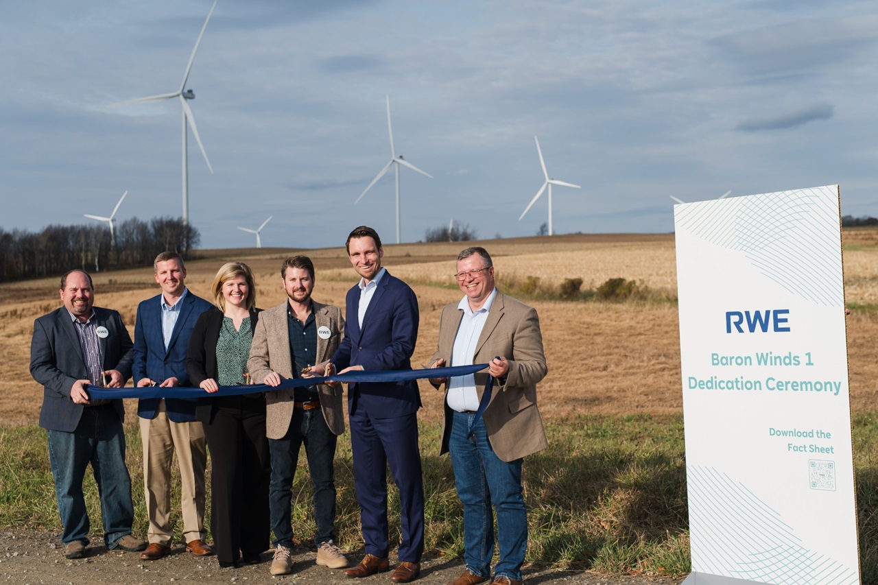 Group of individuals at a ribbon-cutting ceremony for Baron Winds 1, with wind turbines in the background.