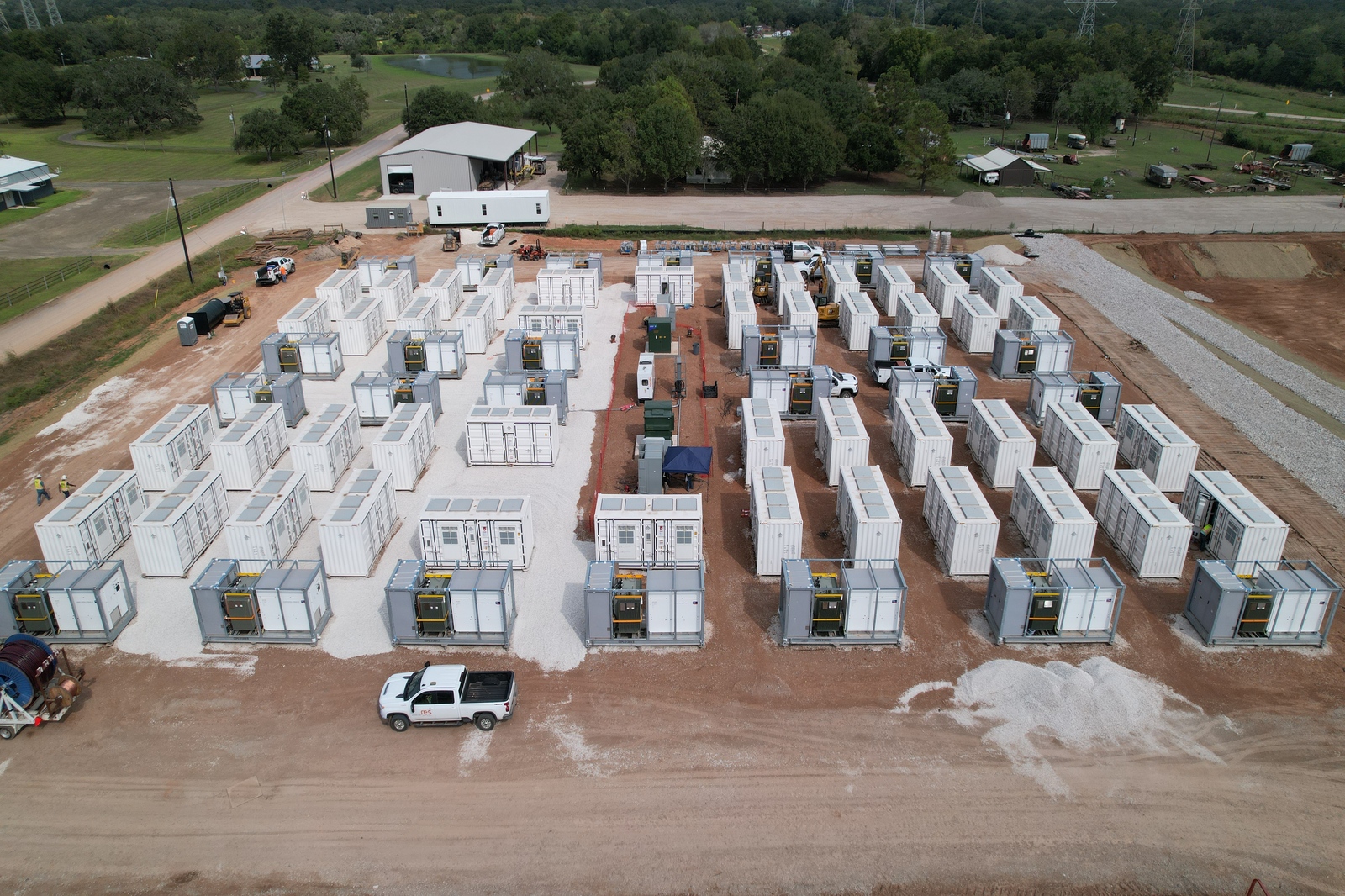 Aerial view of a construction site featuring numerous shipping containers arranged in rows on gravel.