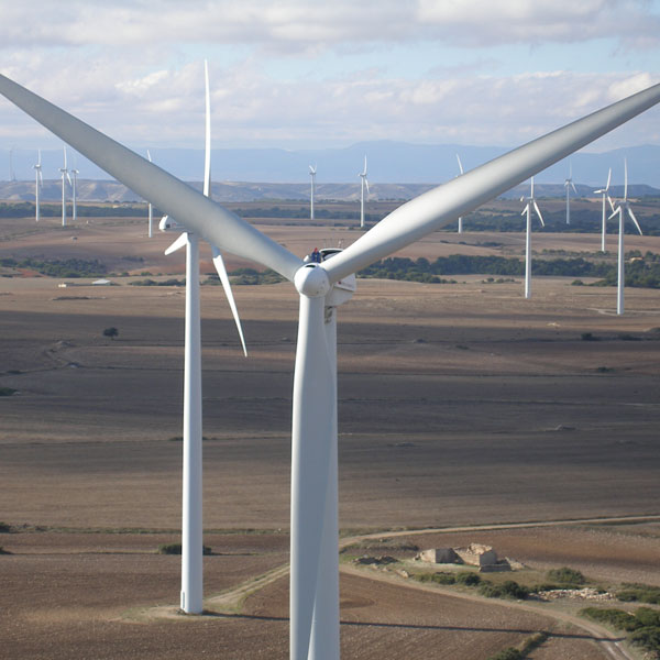 A close-up of a wind turbine with other turbines visible in the background against an open landscape.