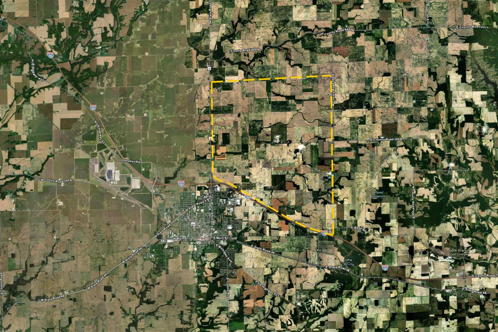 An aerial view showing a patchwork of farmland, roads, and a highlighted area around a town with a grid layout.