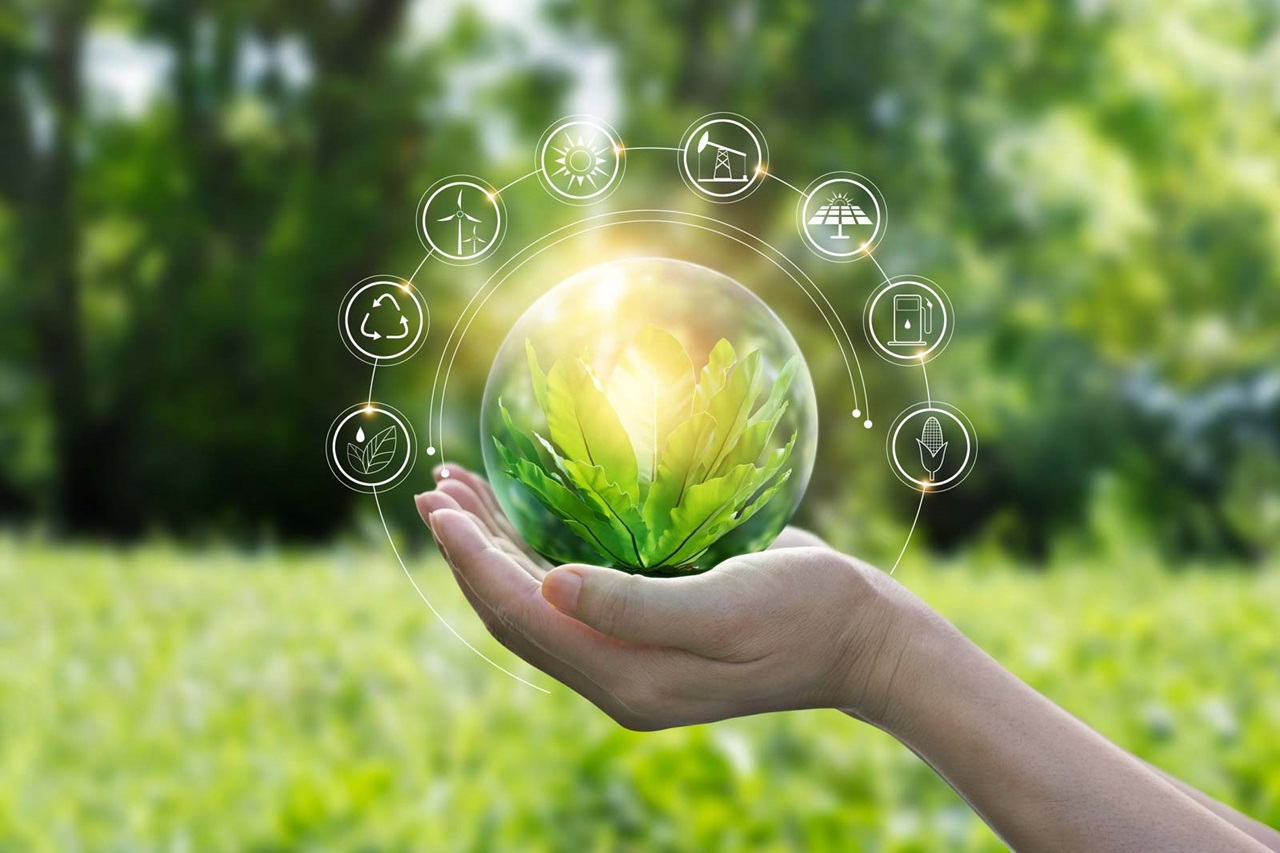 A hand holds a transparent globe with green leaves, surrounded by icons representing renewable energy and sustainability.
