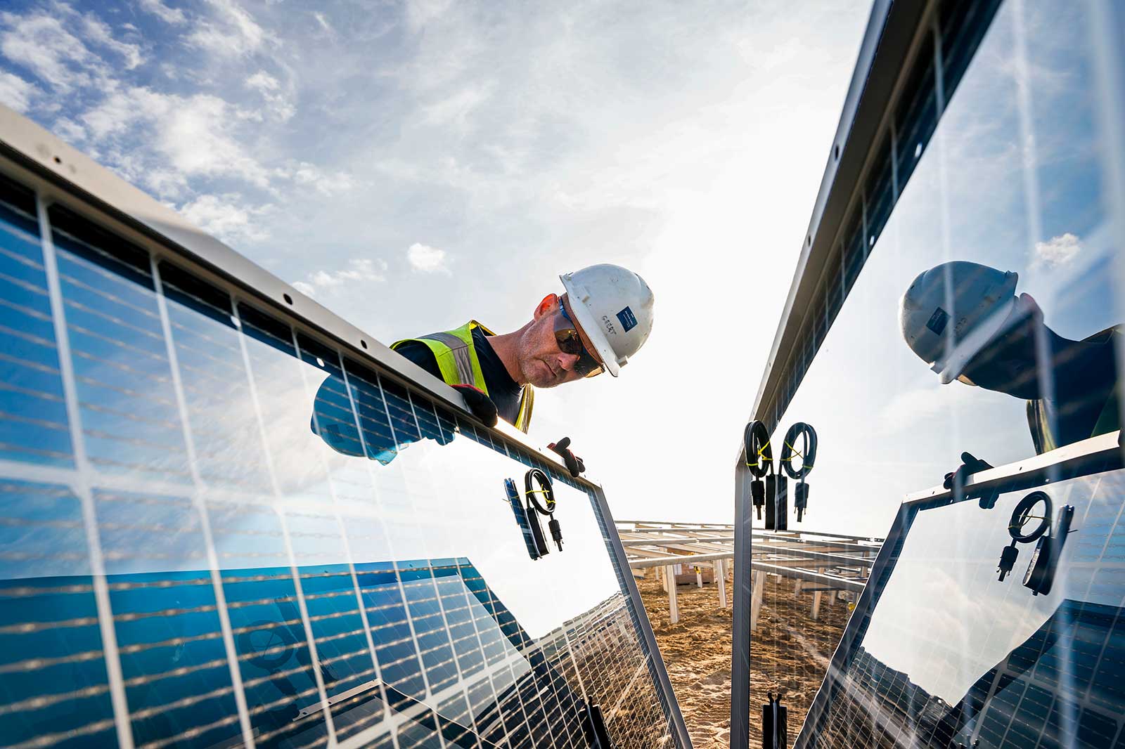 A technician inspects solar panels under a bright sky, showcasing solar technology and renewable energy efforts.