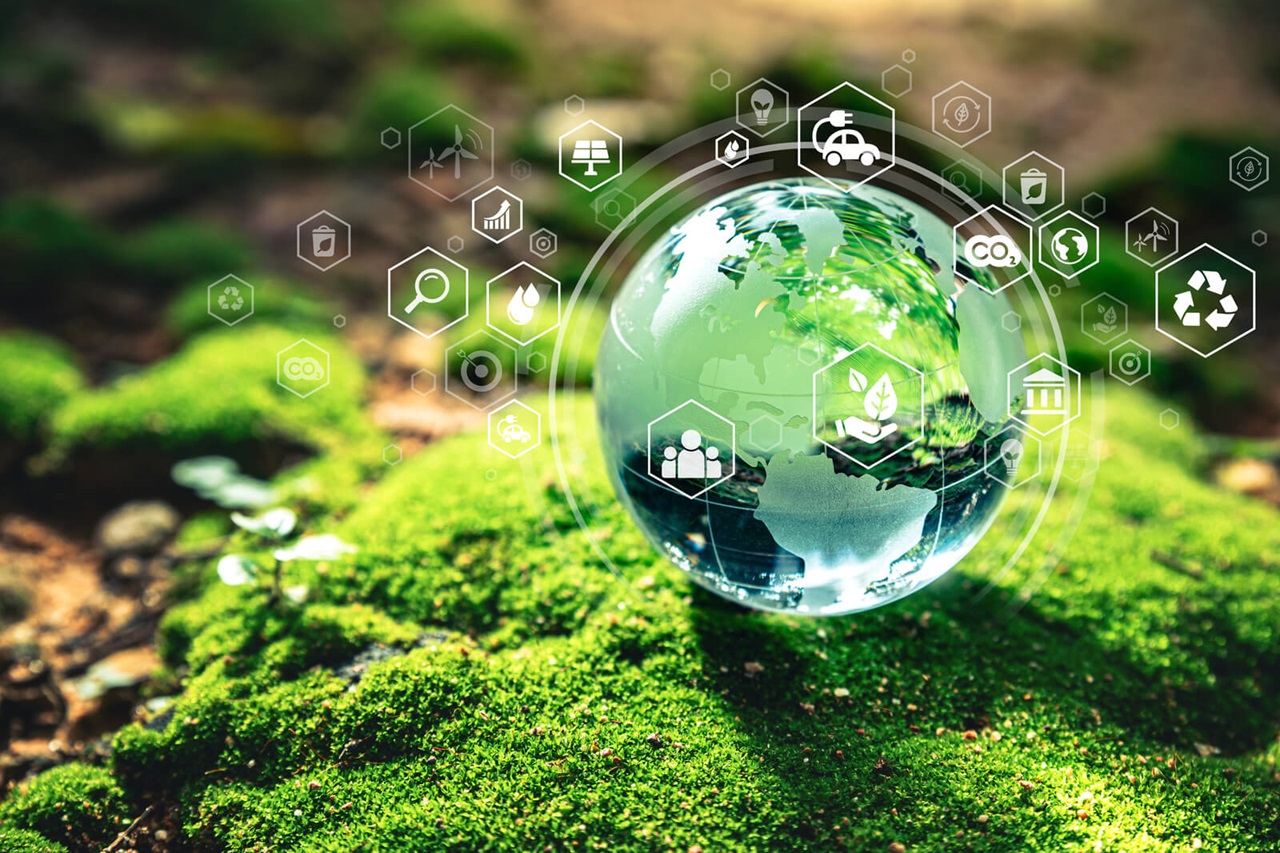 A clear globe representing Earth sits on green moss, surrounded by environmental icons symbolising sustainability and ecology.
