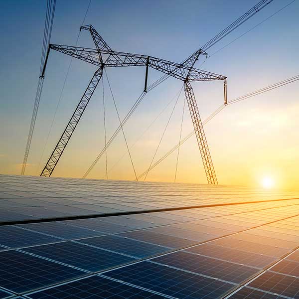 A solar panel field with power lines extending into a sunset. The scene highlights renewable energy integration.