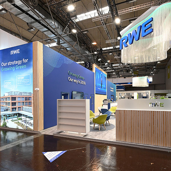 A modern exhibition stand featuring blue panels, wooden accents, and seating, showcasing RWE's strategy for sustainability.