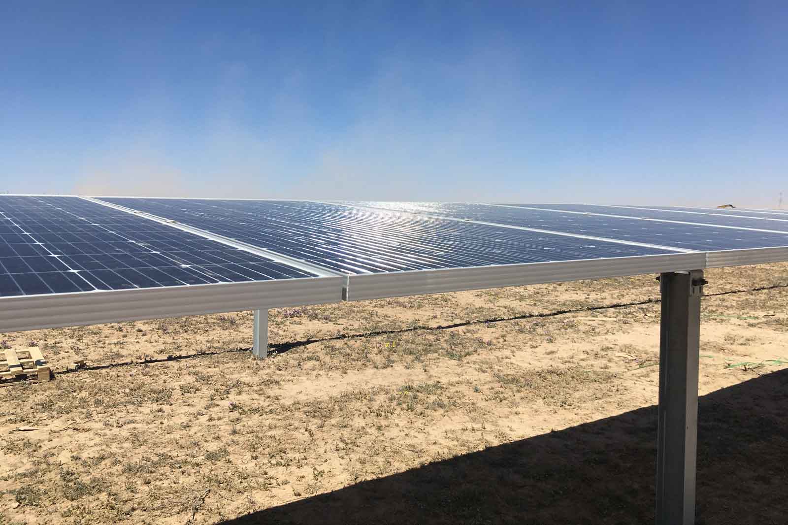 A solar panel on a field reflecting sunlight under a blue sky.